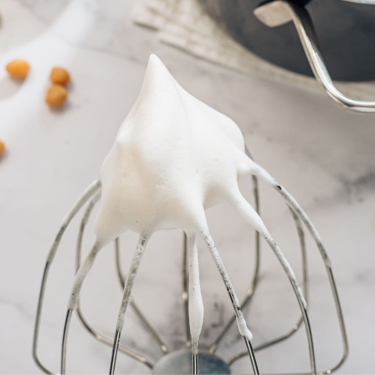 Whipped aquafaba on a whisk.