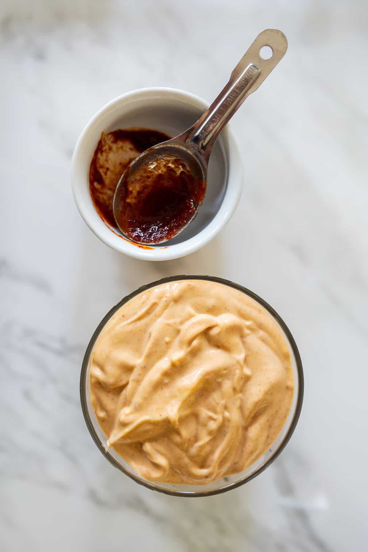 Vegan chipotle mayo in a dish and a teaspoon with chipotle sauce.